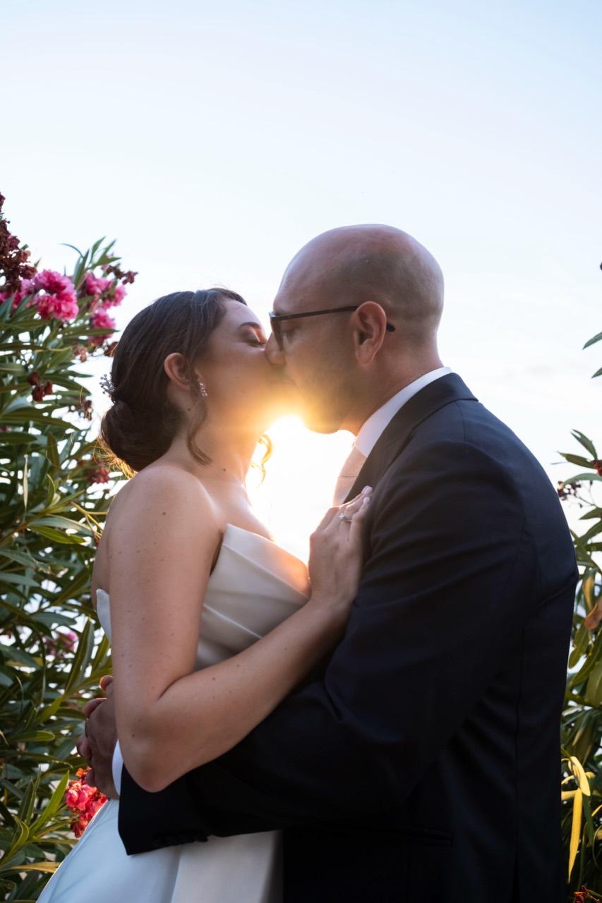 Un bacio degli sposi in controluce al tramonto.