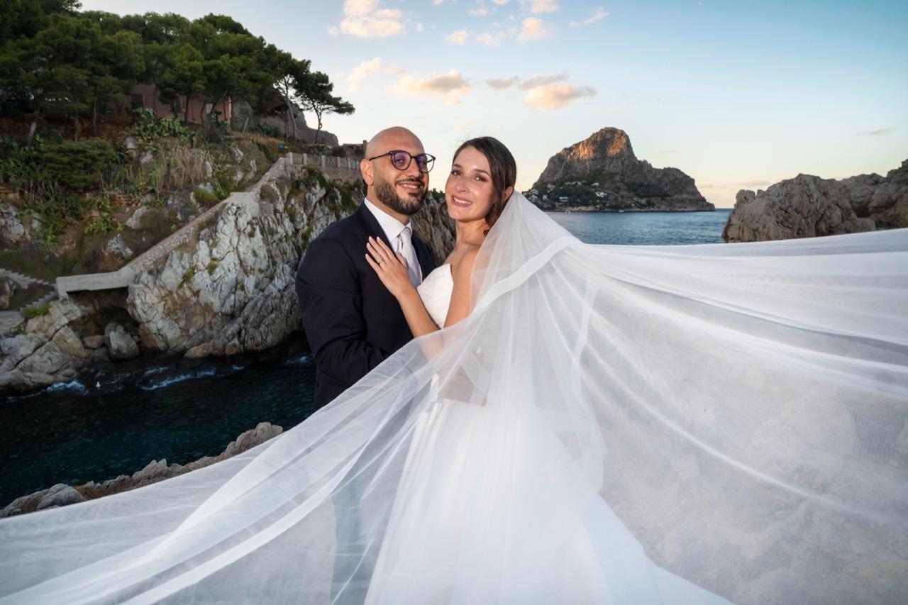 Gli sposi sulla costa rocciosa, avvolti nel velo.
